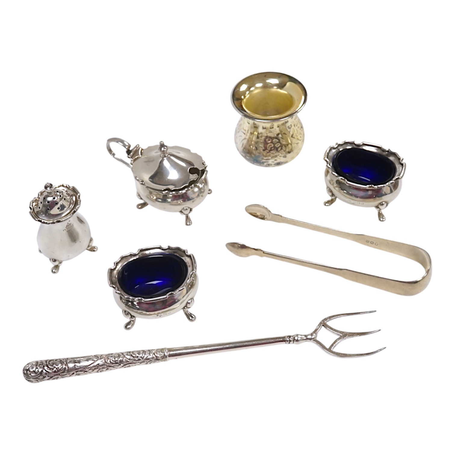 A George V silver four piece condiment set by Adie Bros. Birmingham, 1926 and three other items including a pair of Georgian silver sugar tongs, London 1799. Condition - poor to fair